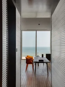 Modern office with wooden flooring, large windows overlooking the sea, and minimalist design.