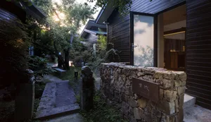 A minimalist residential exterior made of wood and stone.