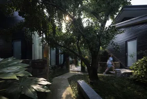 Concrete pathway surrounded by greenery with residential buildings on either side.