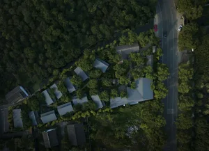 Aerial view of a green urban space with buildings and a road.