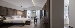 Modern bedroom interior with wooden walls, stone floor, and glass window.