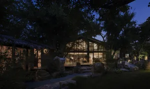 A modern house with a wooden exterior surrounded by nature at dusk.