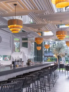 Modern, industrial-style restaurant bar interior with wooden accents and geometric ceiling