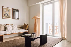 A minimalist living room featuring a daybed, coffee table, and a woven lamp.