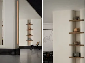 A minimalist living room with wooden shelves, vases, and a speaker, featuring a black ceiling and white walls.