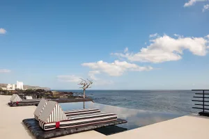 A minimalist poolside view featuring black and white striped fabric cushions.