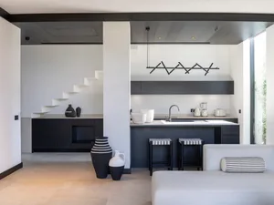 Modern kitchen with black and white color scheme and stone countertops.