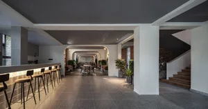 Modern coffee shop interior with concrete flooring, brick structural columns, and potted green plants