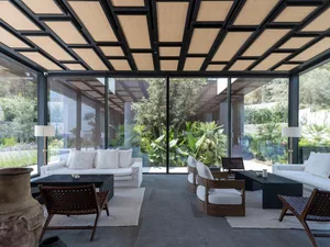A modern living room featuring glass walls and a ceiling with geometric patterns.