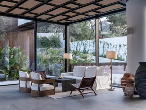 A modern living room with glass walls and wooden furniture.