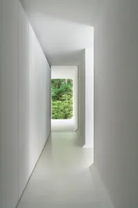 Minimalist corridor with white walls, concrete floor, and steel elements.