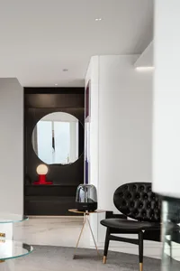 Modern minimalist living room with black marble and white marble accents and a sleek, black chair with golden legs.