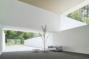 A modern minimalist living room featuring a concrete floor and walls.