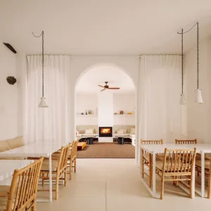 A modern living room with white and beige furniture and a central fireplace.