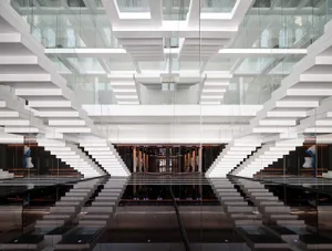 A modern office lobby with glass staircases and a reflective floor.