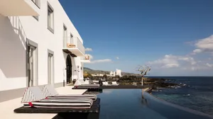 A modern resort with a sea-view poolside reception area, featuring a concrete building with a sleek design.