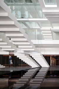 A minimalist modern staircase with glass railings and steps.