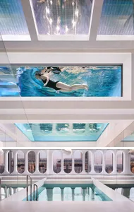 A modern indoor swimming pool with a glass and concrete window design.