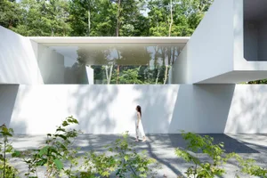 A modern building with white walls, glass walls, and concrete accents.
