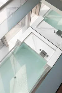 Top-down view of a modern bathroom featuring white marble tiles and glass walls.