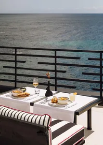 A set table with food and drinks overlooking the ocean.