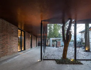 An industrial-style architectural interior with brick walls and a tree in the courtyard.