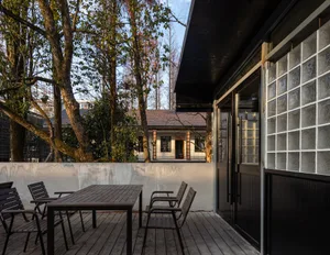 Outdoor patio area with wooden furniture and trees in the background.