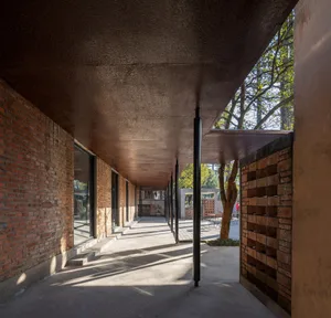 Outdoor pavilion with brick walls, concrete floor, and steel columns.