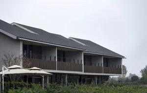 Modern residential building with a wooden balcony and glass windows.