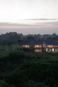 A modern residential home with glass windows and a garden view at sunset.