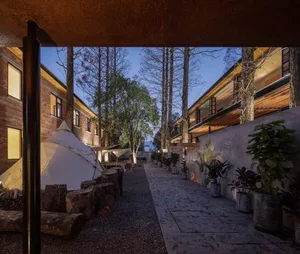A residential building with brick walls, wooden accents, and concrete paths at twilight.