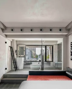 An industrial-style bathroom featuring concrete walls, a glass shower enclosure, and a modern floating sink.