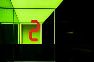 A digital display showing the number 2 in red, illuminated against a bright green background.
