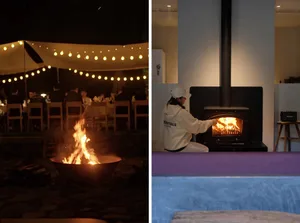 A cozy fireplace interior with a person placing wood in the fire.