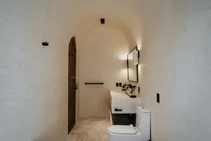 A minimalist bathroom with concrete walls, a white toilet, and a modern sink.