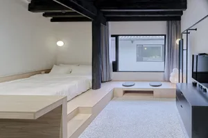 Minimalist bedroom with wood floor, stone accent, and large window.