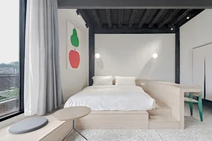 A minimalist bedroom with a bed on a raised platform made of white terrazzo and wood
