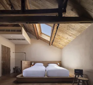 A minimalist bedroom featuring wooden furniture and a skylight.