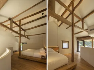 Modern minimalist bedroom with exposed wooden beams, white walls, and a bed on a wooden frame.