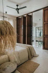 A minimalist bedroom with wooden furniture, fabric bedding, concrete flooring, and glass doors.