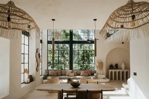 A minimalist living room with concrete walls, a large window, and rattan pendant lights.