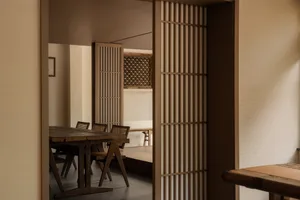 Modern minimalist dining room featuring a wooden table and chairs, with an emphasis on clean lines and simple design.