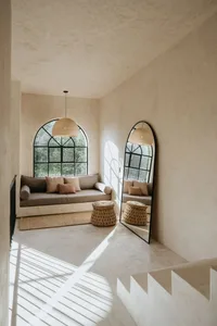 A minimalist living room with a concrete floor, wicker furniture, and fabric cushions and pillows.