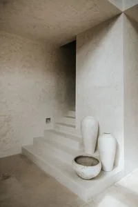 A minimalist stairwell with concrete steps, walls, and vases in a neutral color palette.