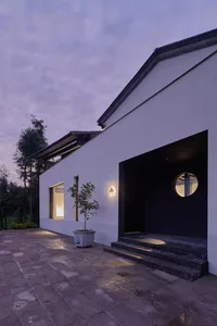 A minimalist white house with concrete steps and a circular window.