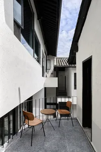 Modern balcony featuring black metal bars, concrete floor, and wooden furniture.