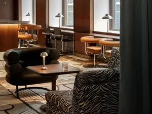 A stylish modern bar and cafe seating area with leather stools and tables, metal accents, and wooden finishes.