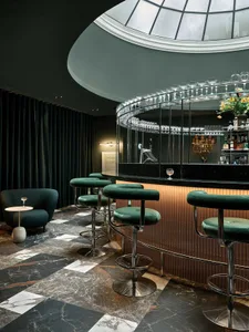 Bar with green stools, marble flooring, and dark green curtains.