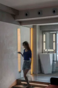 A modern bathroom featuring concrete, glass, and stainless steel materials with an open space design.