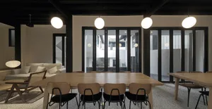 Modern dining room with wooden tables, fabric chairs, and glass walls
